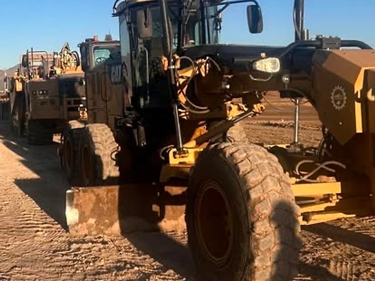 Close view of a Caterpillar motor grader blade working graded soil