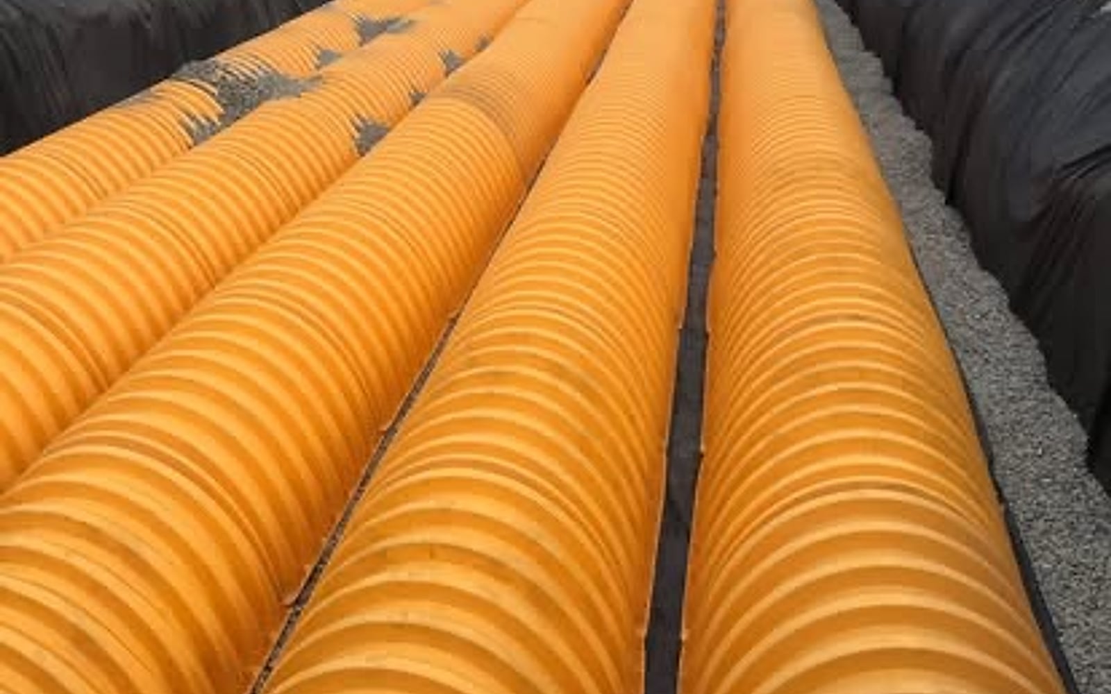 Rows of large corrugated culvert pipe set in a lined trench for a drainage installation